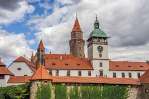 Bouzov Castle with red-tiled roofs, ivy-covered walls and towers under cloudy sky
