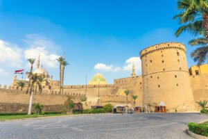 Cairo Citadel walls, mosque domes and palm trees under blue sky