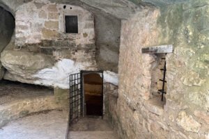 Interior cave room with iron gate and stone steps at Castello bizantino di Angelokastro