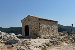 Stone chapel at Castello bizantino di Angelokastro on a rocky hilltop with distant mountains