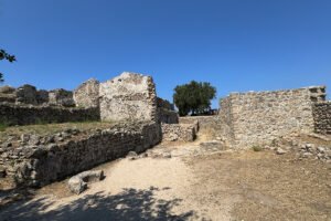 Ruined stone walls at Castello bizantino di Angelokastro on hilltop under blue sky