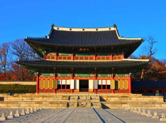 Front view of Changdeokgung Palace with autumn trees and blue sky