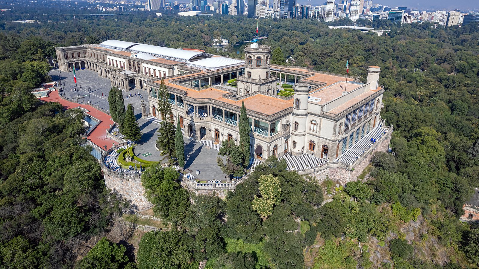 Aerial view of Chapultepec Castle perched above forested Chapultepec Park with Mexico City skyline