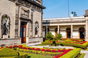 Chapultepec Castle courtyard with trimmed hedges and red flowers