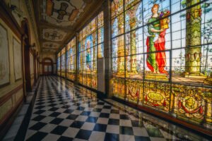 Stained-glass corridor inside Chapultepec Castle with checkered marble floor