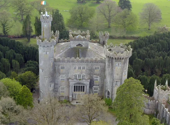 Aerial view of Charleville Castle surrounded by yew trees and Irish flag