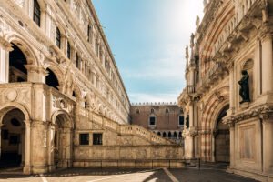 Sunlit courtyard of Doge's Palace with ornate arches and grand staircase in Venice