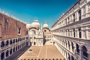 Doge's Palace courtyard with ornate arcades and domes under blue sky