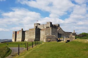 Dover Castle viewed from grassy slope under cloudy blue sky