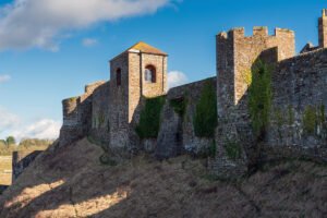 Dover Castle stone walls and towers on grassy cliff under blue sky