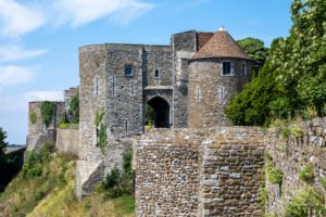 Dover Castle stone gate and round towers above grassy cliff under blue sky
