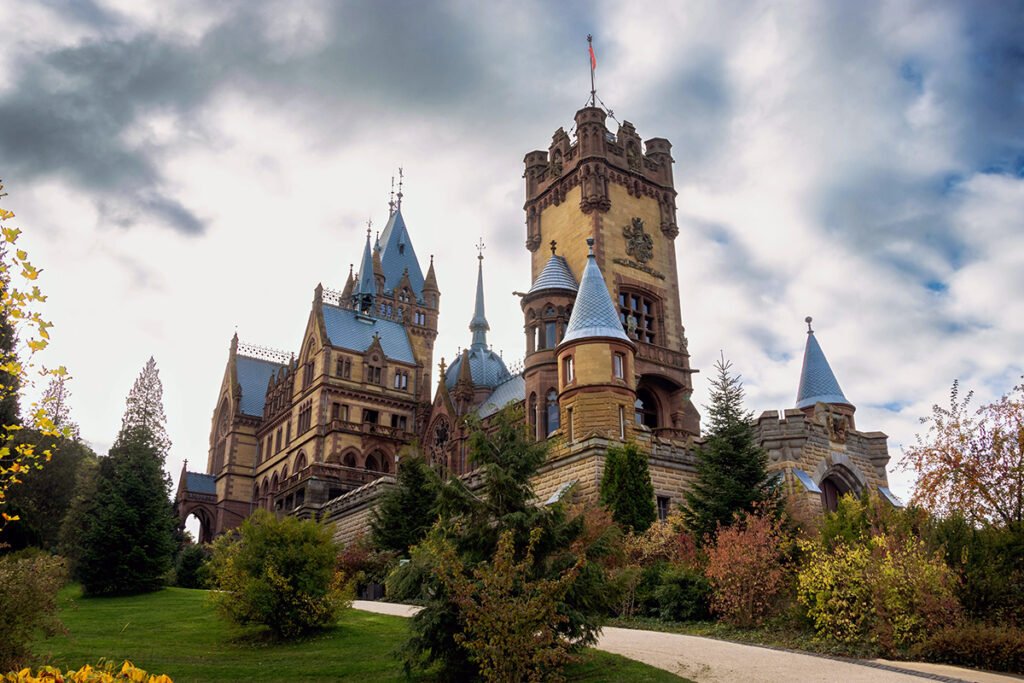Drachenburg Castle seen from sloping garden path under cloudy sky