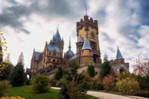 Drachenburg Castle seen from sloping garden path under cloudy sky
