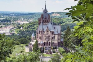 Drachenburg Castle on hill surrounded by forest and valley views