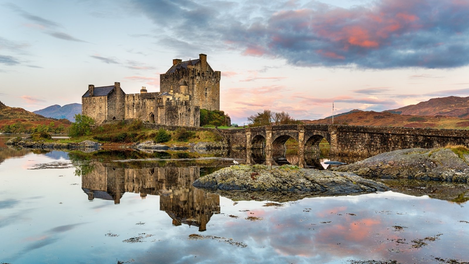 Eilean Donan Castle reflected on calm sea at sunset