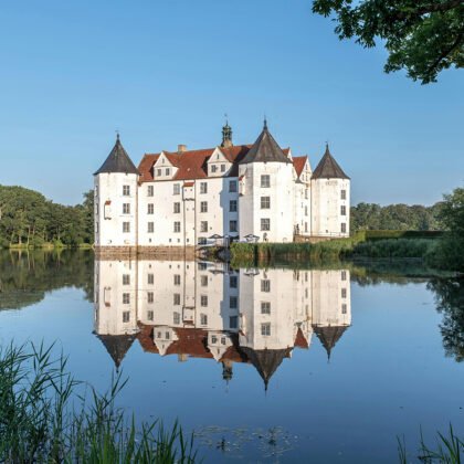 Glücksburg Castle reflected in calm lake at sunrise
