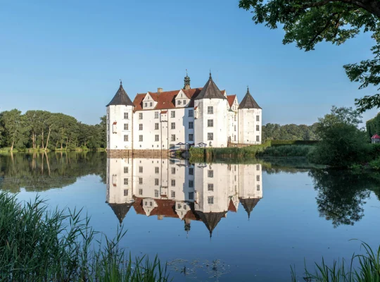 Glücksburg Castle reflected in calm lake at sunrise