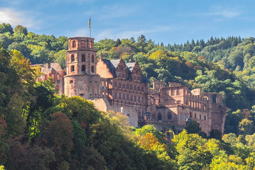 Heidelberg Castle ruins perched above forested hillside under blue sky