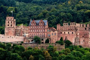 Heidelberg Castle ruins rising above lush green hillside and trees