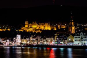 Heidelberg Castle glowing above riverside night town