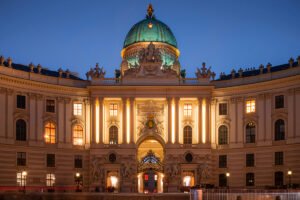 Hofburg Palace illuminated at dusk with green copper dome and ornate façade