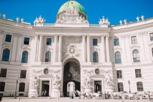 Hofburg Palace façade with green dome and horse carriages