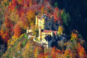 Hohenschwangau Castle perched amid vibrant autumn forest