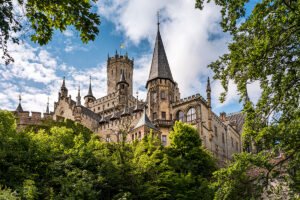 Marienburg Castle spires framed by trees under blue sky