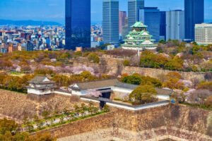Osaka Castle and moat with cherry blossoms and city skyscrapers