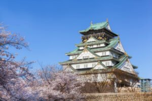 Osaka Castle with cherry blossoms under blue sky