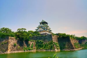 Osaka Castle perched above stone walls and green moat