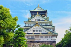 Osaka Castle framed by green trees under blue sky