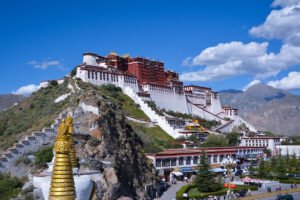 Potala Palace atop a rocky hill with blue sky and surrounding buildings