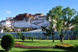Potala Palace on hill above manicured gardens under blue sky
