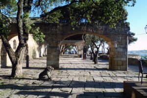 Stone archways at São Jorge Castle terrace with trees and river view