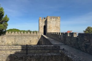 View of São Jorge Castle stone walkway and tower under blue sky