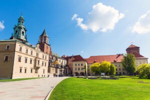 Wawel Castle courtyard and towers under blue sky with green lawn