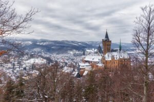Snow-covered Wernigerode Castle above town and Harz hills
