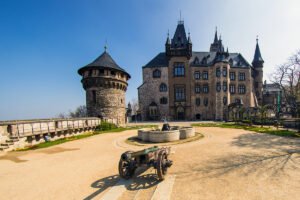 Wernigerode Castle exterior with cannon and tower under blue sky