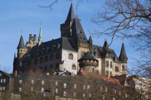 Wernigerode Castle towers above winter trees under blue sky