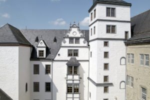 Exterior courtyard view of Wolfsburg Castle white walls and tower under blue sky