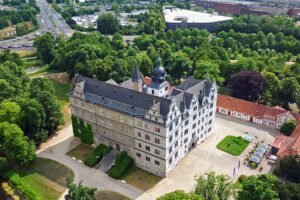 Aerial view of Wolfsburg Castle surrounded by trees and courtyard