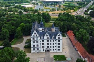 Aerial view of Wolfsburg Castle surrounded by trees and lake