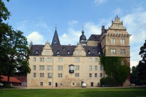 Wolfsburg Castle exterior with towers, ivy, and blue sky