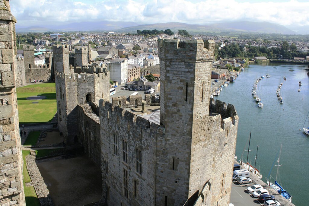 Caernarfon Castle towers beside river and moored boats