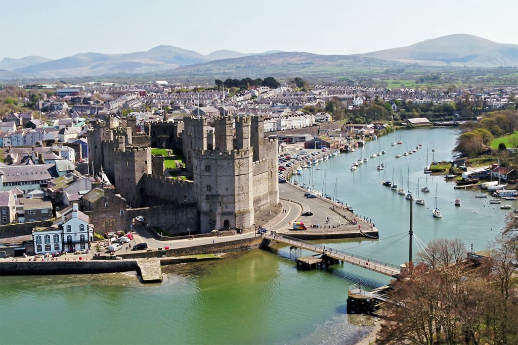 Aerial view of Caernarfon Castle beside river and marina