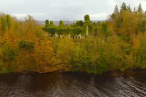 Overgrown ruins of Castle Caldwell by river in autumn