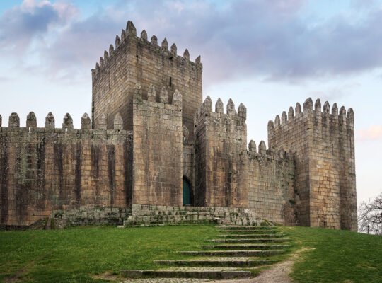 Castle of Guimaraes towers over green hill at dusk