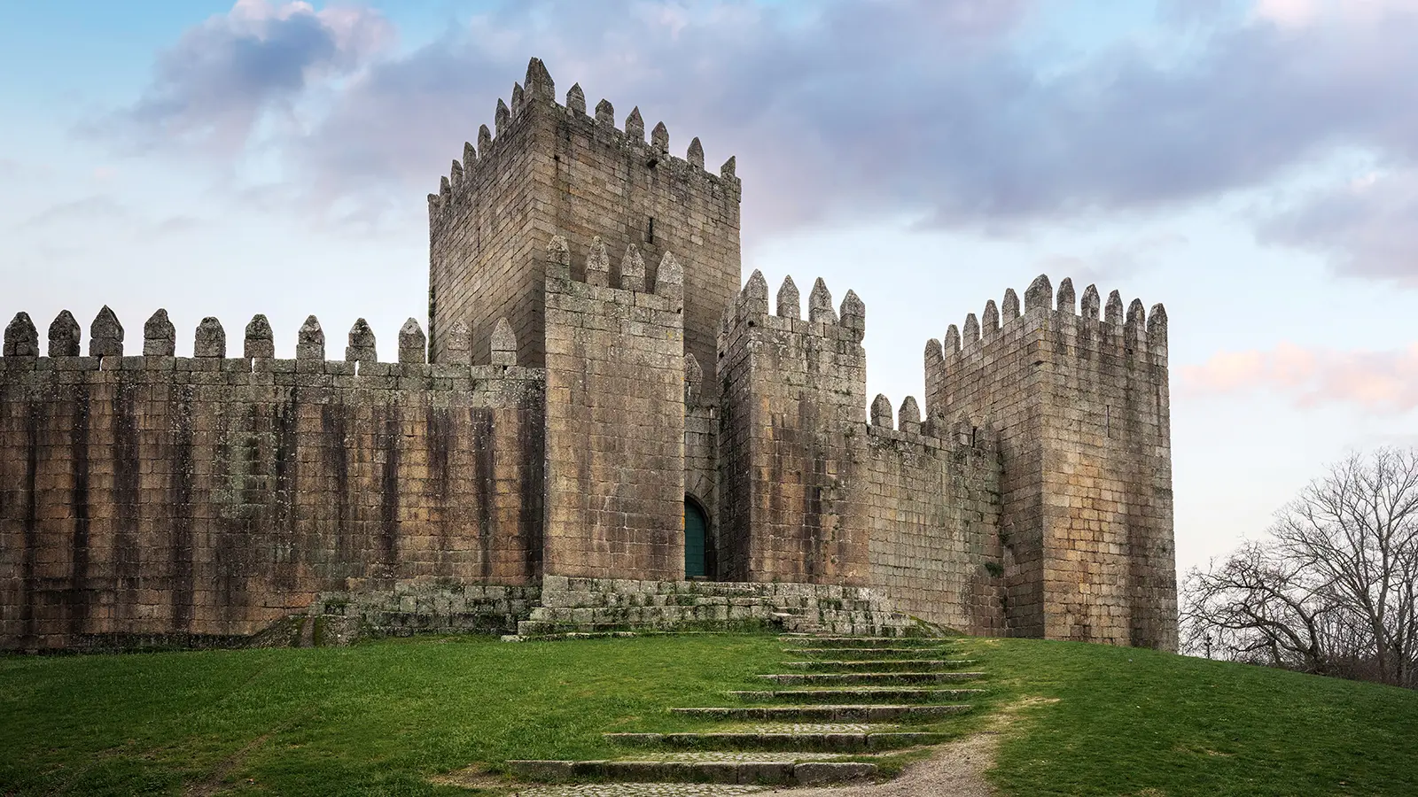 Castle of Guimaraes towers over green hill at dusk
