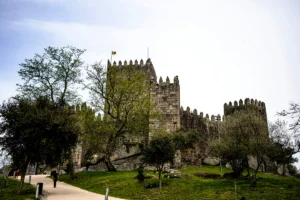Stone battlements and towers of the Castle of Guimaraes atop green hill